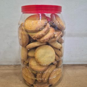 A large transparent plastic jar with a red lid filled to the top with round golden-baked Usmania cookies.