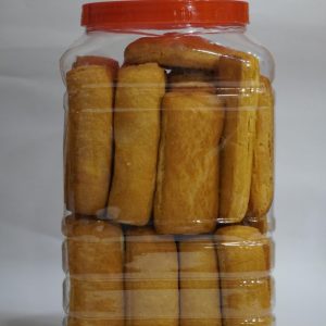 Crispy golden-brown bakery maskas / toast biscuits neatly stacked inside a clear plastic jar with a red lid.