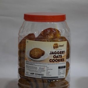 Cakey & Cookie Bakers Jaggery Oats Cookies stored in a clear plastic jar with a red lid, displaying label with product details.